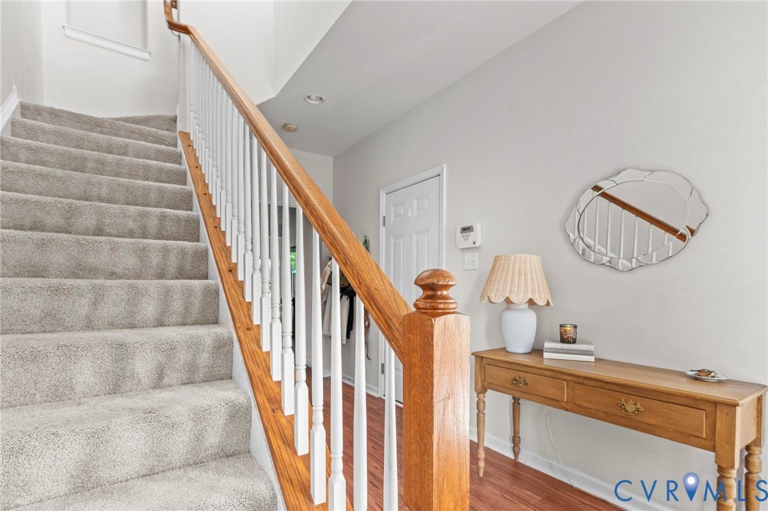 Elegant staircase featuring a warm wood handrail and newel post with white balusters, hardwood flooring, and soft recessed lighting