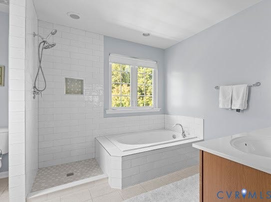 Walk-in shower with subway tile surround and built-in niche, separate soaking tub with tiled surround, and single vanity with integrated sink