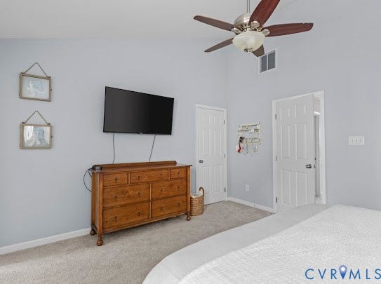 Vaulted ceiling, ceiling fan with integrated lighting, two white panel doors, wall-mounted television, and light gray wall finish