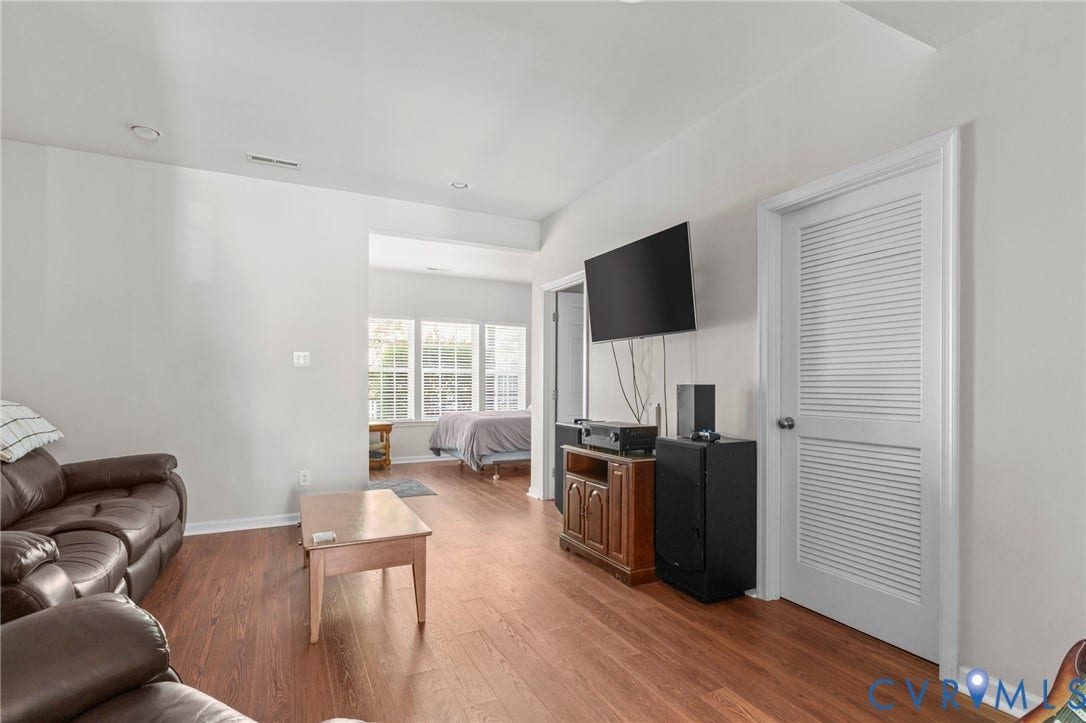 Bright, open living area featuring hardwood flooring, recessed ceiling lighting, and large multi-pane windows allowing natural light throughout