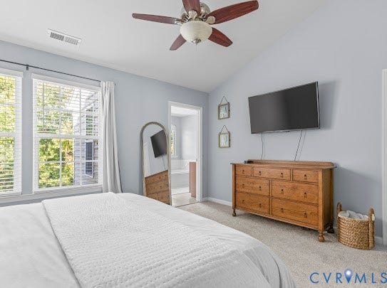 Vaulted ceiling with a ceiling fan, dual windows, and carpet flooring