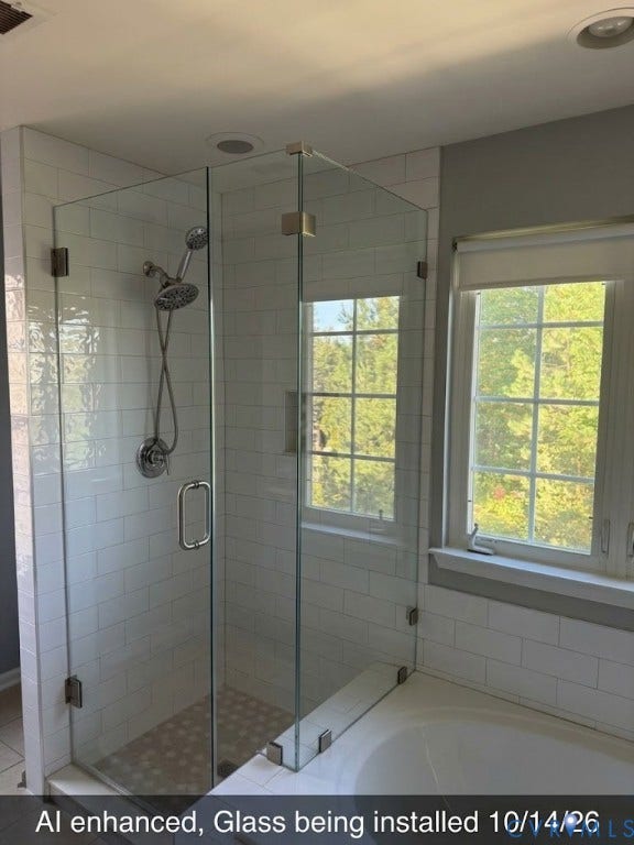 Glass-enclosed shower with subway tile surround, mosaic shower floor, and dual shower heads