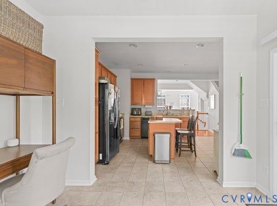 Kitchen featuring wood cabinetry, stainless steel appliances, and a central island with bar seating