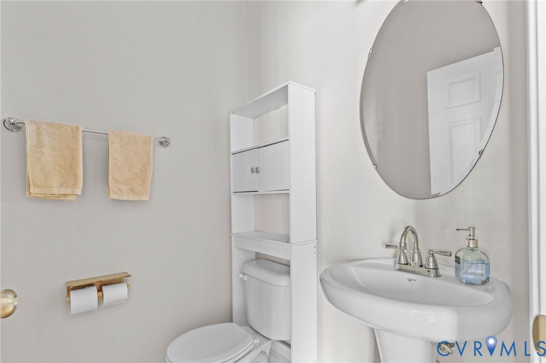 Pedestal sink with chrome-finish faucet, oval mirror, and wall-mounted shelving