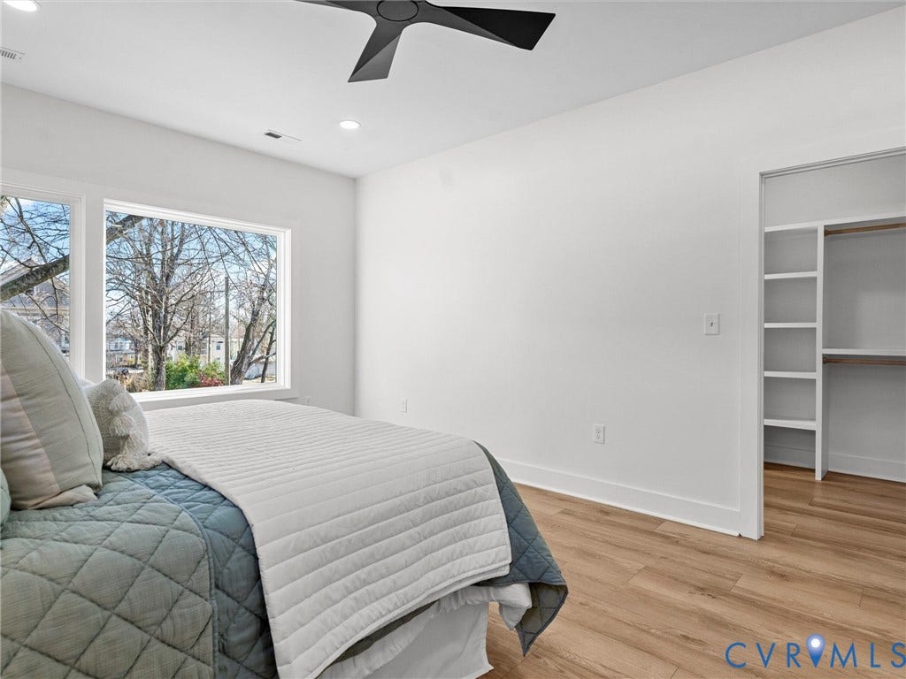 2202 3rd Avenue, Northside, Richmond, VA 23222 Large window with white trim, wood-finish flooring, built-in closet shelving, and a ceiling fan with integrated lighting