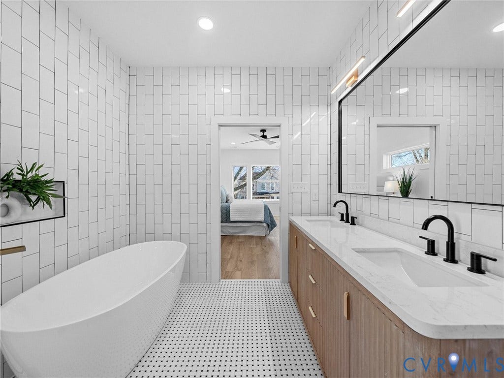 2202 3rd Avenue, Northside, Richmond, VA 23222 Freestanding soaking tub, dual-sink vanity with wood-finish cabinetry, black-framed mirror, and white subway tile walls