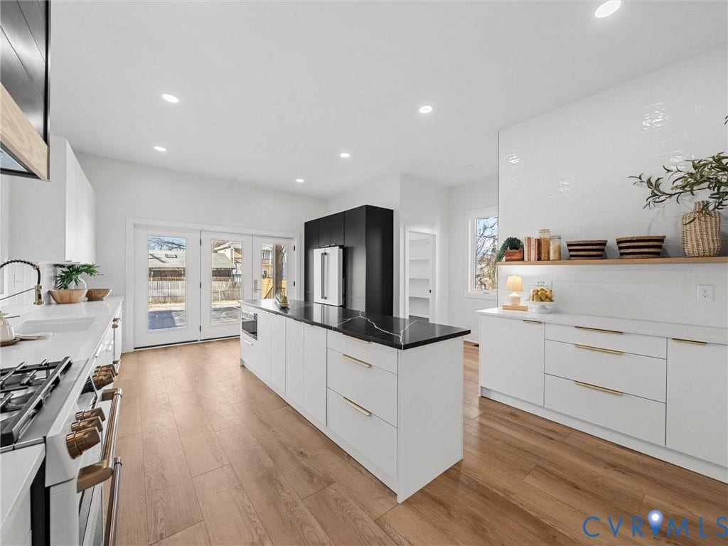 2202 3rd Avenue, Northside, Richmond, VA 23222 Kitchen featuring wood-finish flooring, white cabinetry with gold-tone hardware, a center island with a dark countertop, white quartz countertops, and a white tiled backsplash