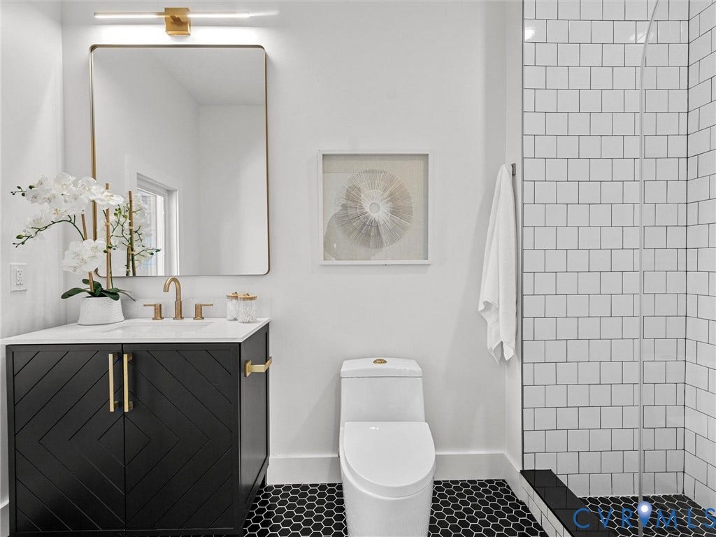 2202 3rd Avenue, Northside, Richmond, VA 23222 Black hexagonal floor tiling, freestanding vanity with brass hardware, undermount sink with brass-finish faucet, subway-tiled shower with glass enclosure