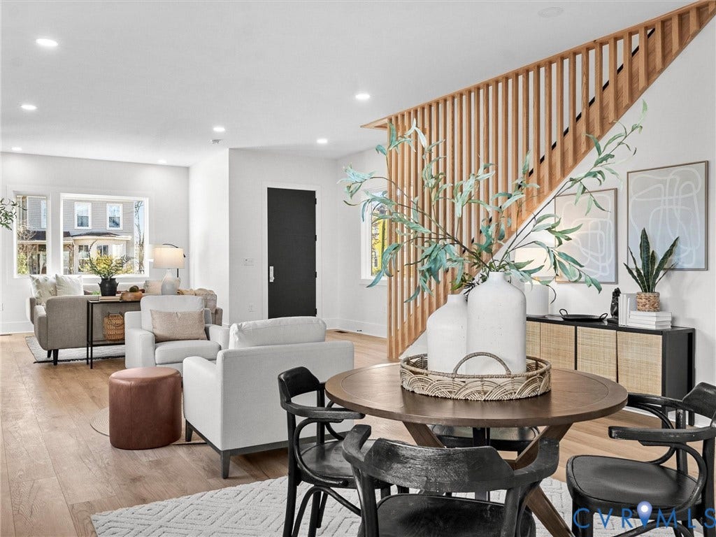 2202 3rd Avenue, Northside, Richmond, VA 23222 Open-concept living space featuring a round wood-finish dining table with black chairs, a white upholstered seating area, and warm wood-finish flooring throughout