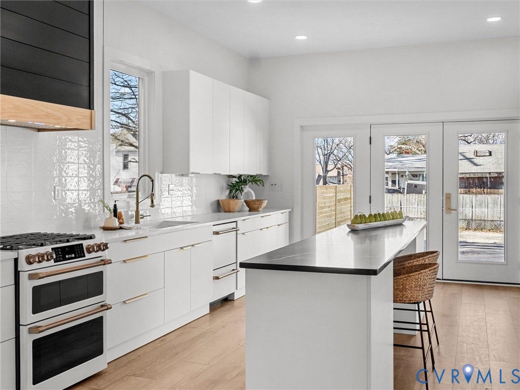 2202 3rd Avenue, Northside, Richmond, VA 23222 Contemporary kitchen with light wood-finish flooring, white flat-panel cabinetry, a black and wood-finish range hood, and a white tile backsplash