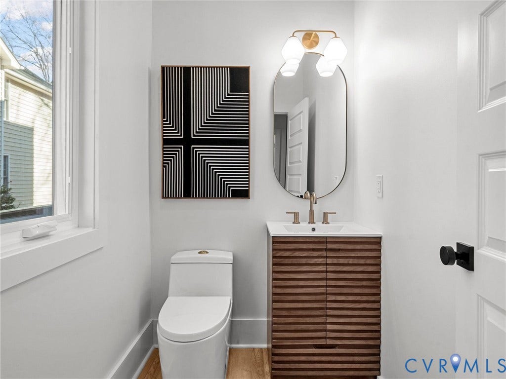 2202 3rd Avenue, Northside, Richmond, VA 23222 Powder room featuring a wood-finish vanity with a white countertop and rectangular sink, gold-finish faucet, and an oval mirror