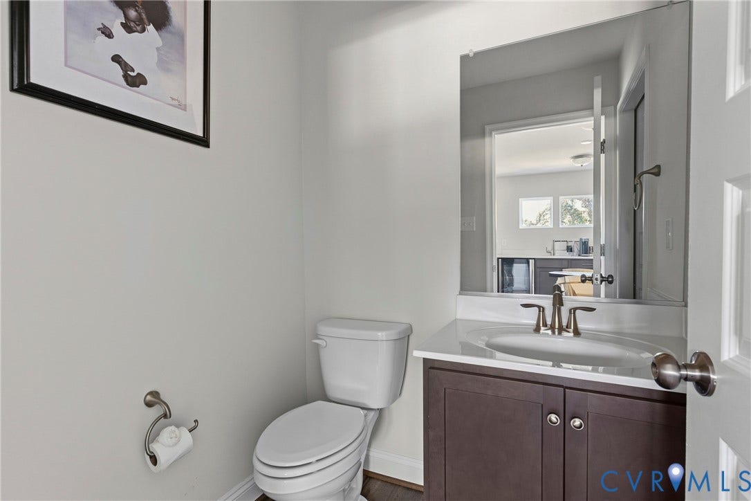 Elegant half bath featuring a dark wood-finish vanity with dual cabinet doors, white porcelain sink, and brushed nickel hardware