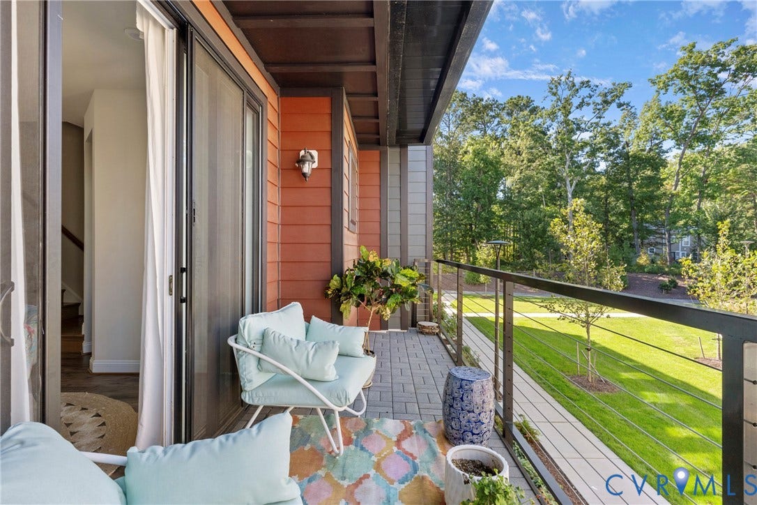 Expansive composite deck with cable railing system overlooking manicured lawn and mature tree-lined landscape