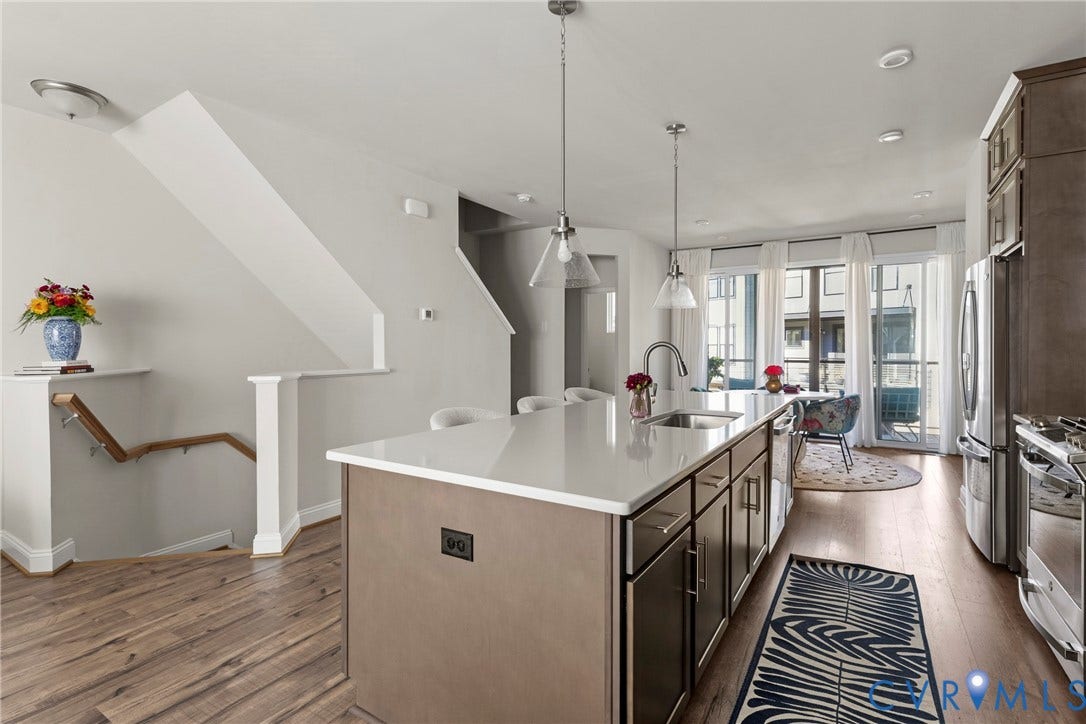 Modern kitchen featuring a large center island with white quartz countertops, stainless steel appliances, and pendant lighting