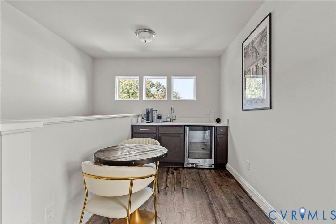 Built-in wet bar with dark wood cabinetry, light-toned countertop, and stainless-steel beverage cooler