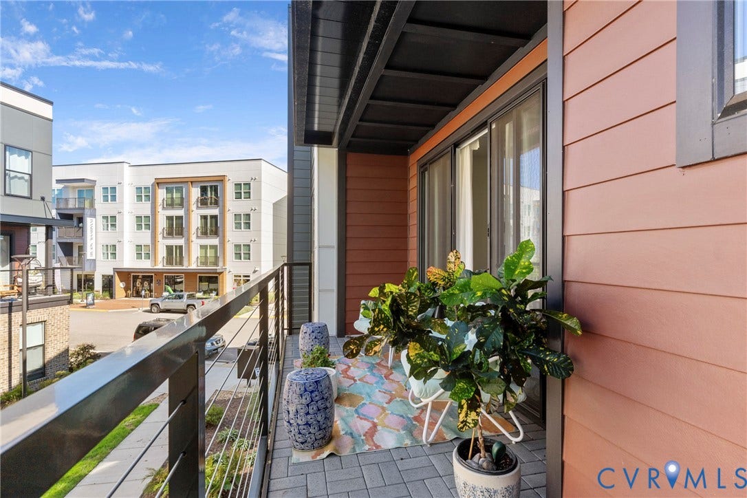 Modern balcony featuring composite decking, cable railing system, and substantial planter beds with integrated greenery