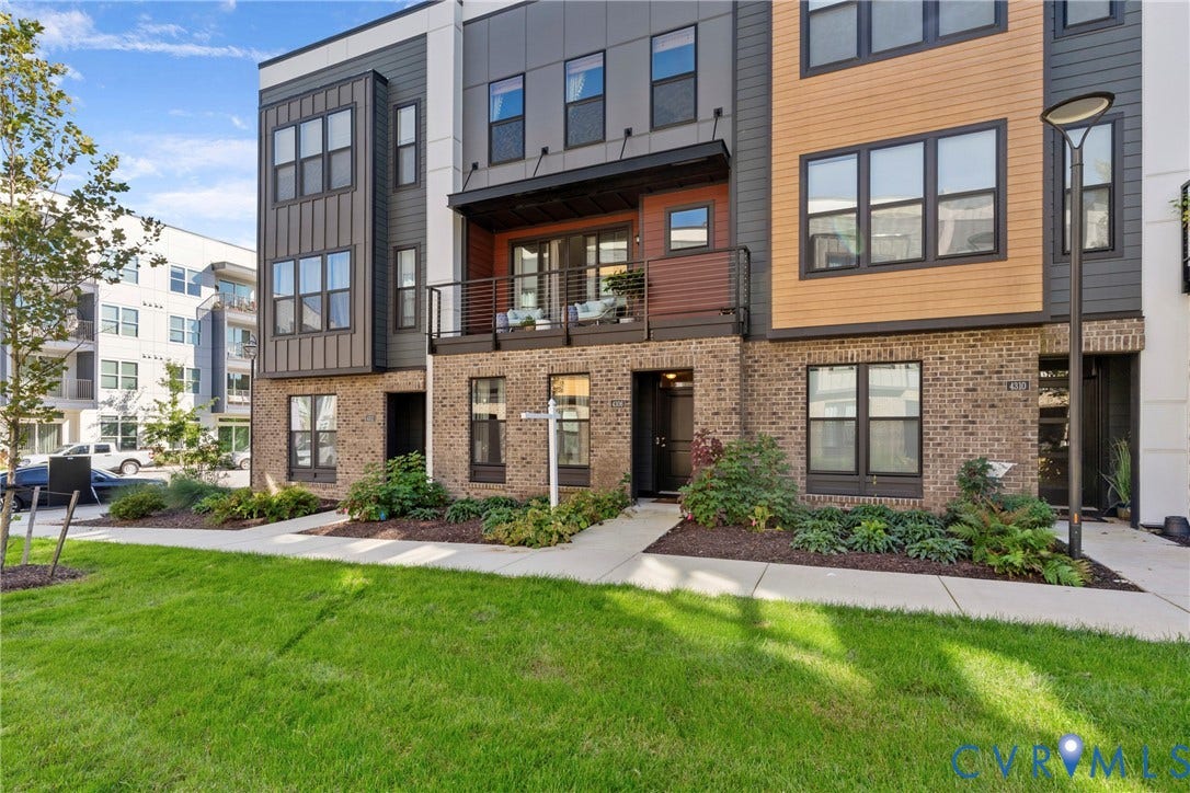 Contemporary exterior with brick and panel siding, featuring a private balcony, integrated landscaping, and a sidewalk entry