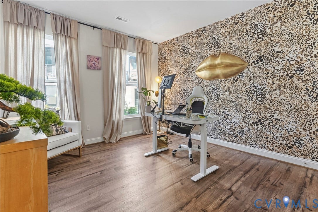 Wood-finish flooring, accent wall, multiple windows, white baseboards, recessed lighting