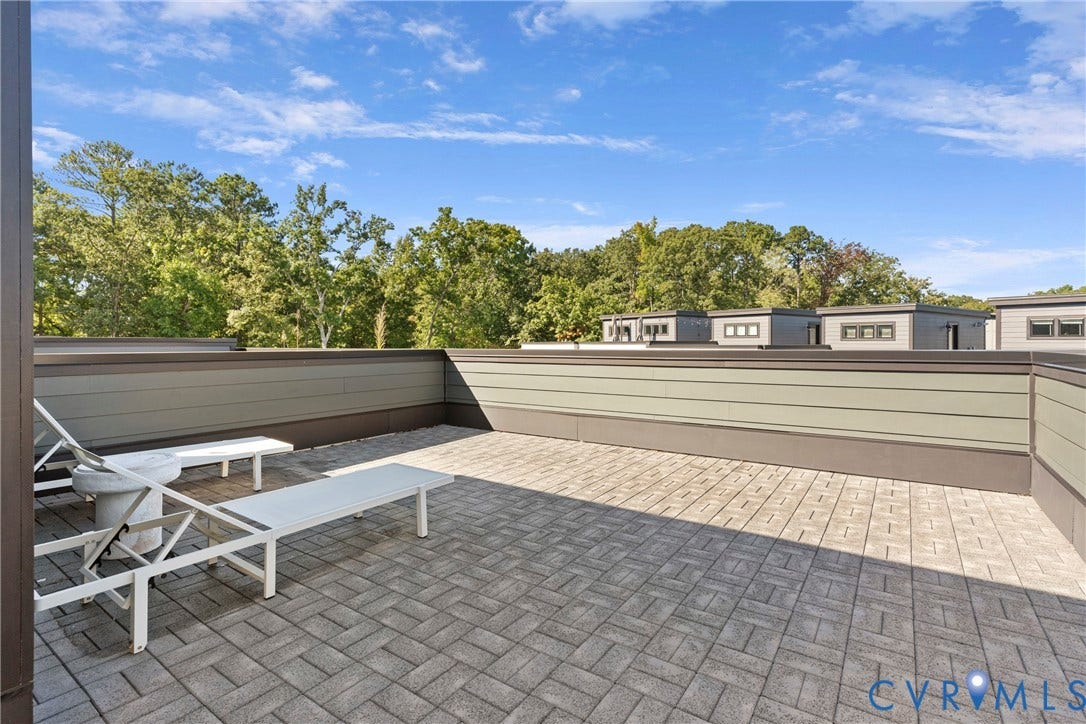 Expansive outdoor patio featuring paver flooring and a partial privacy wall