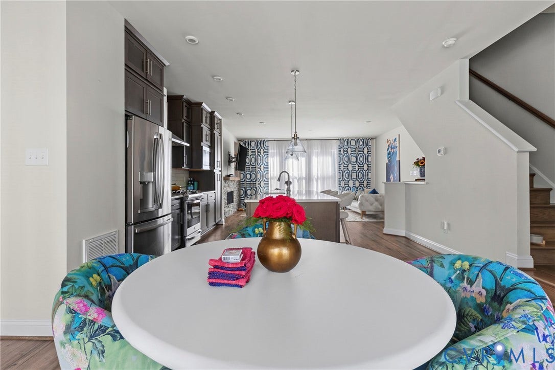 Stainless steel appliances, wood-finish flooring, dark wood cabinetry, recessed lighting, and a staircase with wood treads