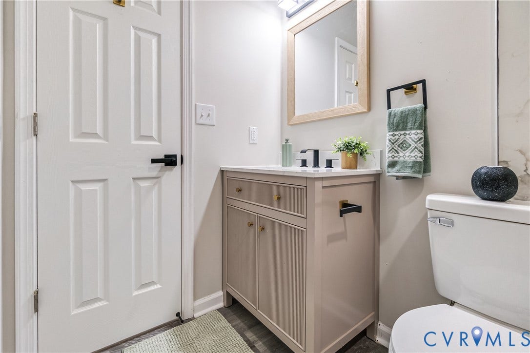 Vanity with a light-colored countertop, wood-finish flooring, a toilet, and a paneled door