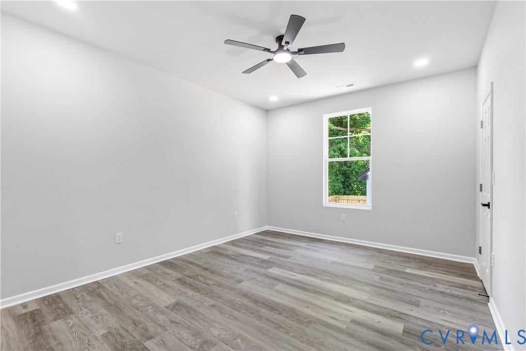 Spacious room featuring wood-finish flooring, recessed lighting, a modern ceiling fan, and a double-hung window
