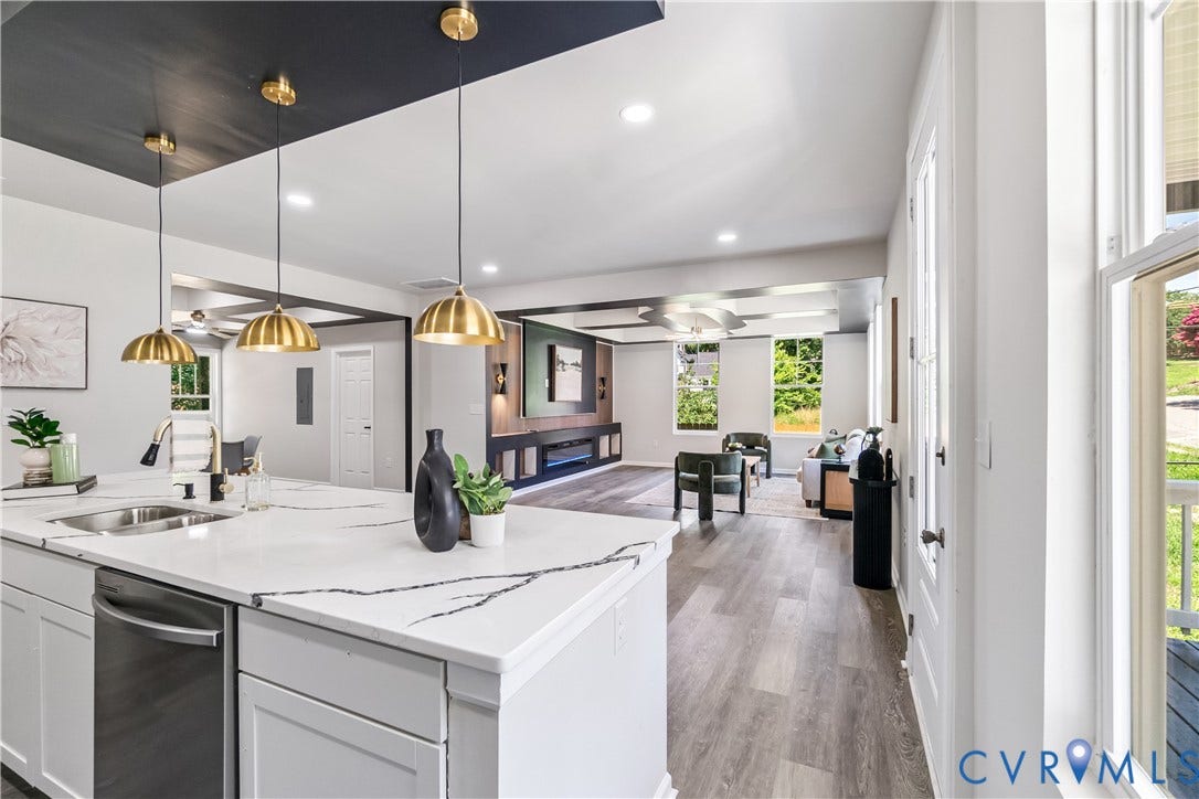 Kitchen island with a built-in sink and integrated dishwasher, pendant lighting, wood-finish flooring, and recessed lighting