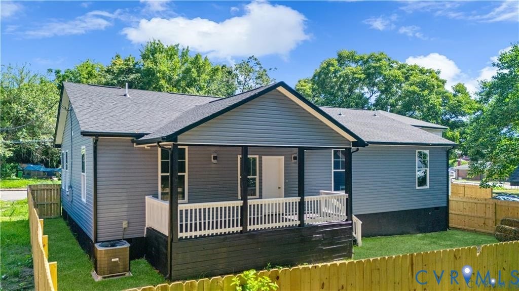 Gray siding exterior with white trim, covered front porch, white railing, and a fenced yard