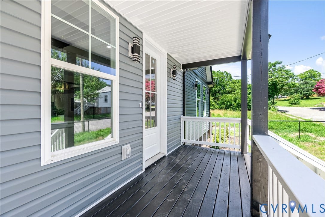 Front porch with dark wood-finish decking, white railings, and gray horizontal siding