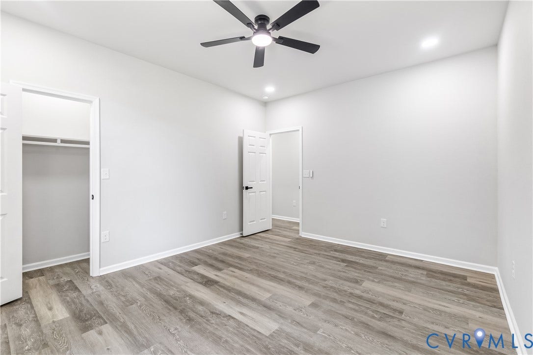 Wood-finish flooring, ceiling fan with integrated lighting, recessed ceiling lights, and white interior doors