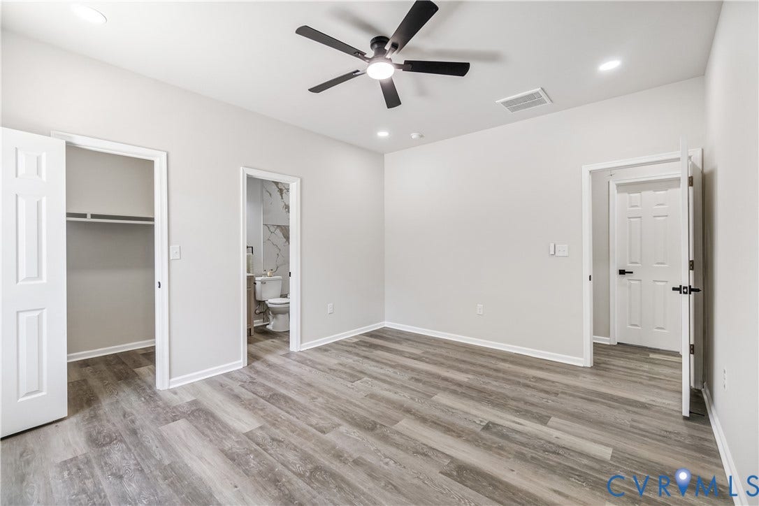 Recessed lighting, ceiling fan, wood-finish flooring, white doors, and a partial bathroom with tile wall accents