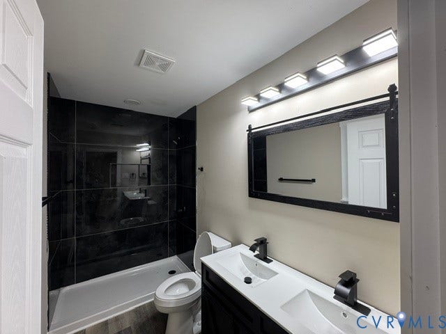Dual sink vanity with matte black faucets, framed mirror, and contemporary light fixture