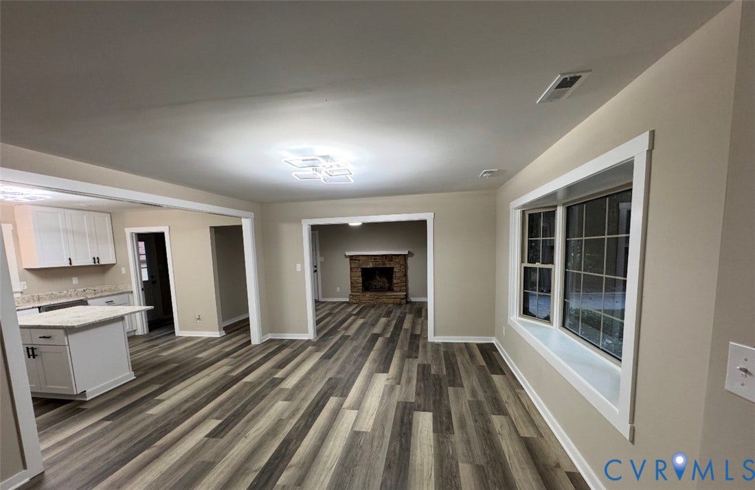 Wood-finish flooring throughout, bay window with white trim, recessed lighting, and a modern ceiling fixture