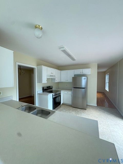 Kitchen featuring white cabinetry, stainless steel appliances, a double basin sink, and counter space with a breakfast bar