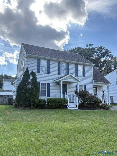 Light-colored siding exterior, dark shingle roof, blue window shutters, front porch with white railing, and established landscaping
