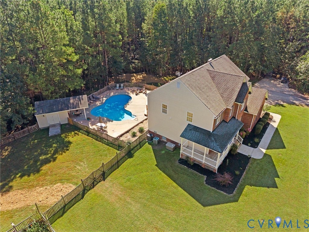 Spacious property featuring an in-ground swimming pool, a pool house, a covered porch, and mature landscaping