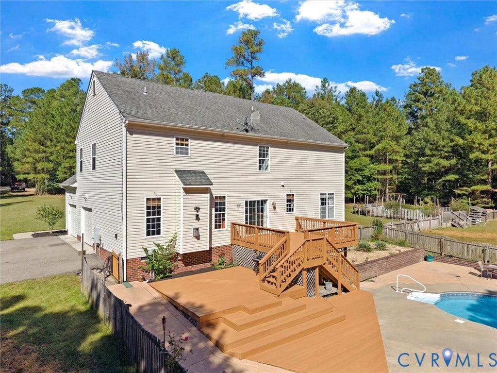 Multi-level wood-finish deck with integrated steps, direct access to the concrete patio, and in-ground pool