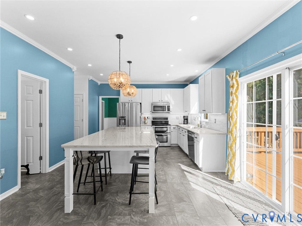 White shaker cabinetry, recessed lighting, stainless steel appliances, sliding glass doors, and a kitchen island with pendant lighting
