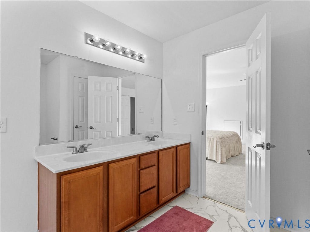 Dual vanity with integrated sinks, wood-finish cabinetry, and a large mirror