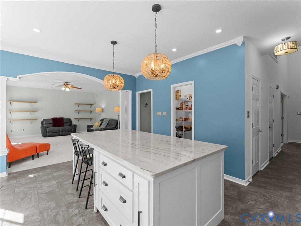 Kitchen island with a light-toned countertop, recessed lighting, decorative pendant lights, and tile flooring