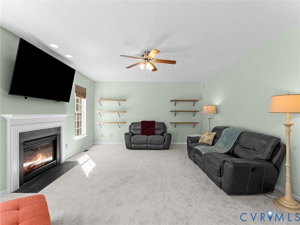 Spacious room featuring a fireplace with a white mantel, ceiling fan, recessed lighting, and wall-mounted shelving
