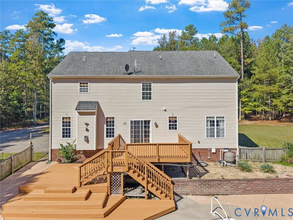 Multi-level wood deck with integrated steps, siding exterior, brick foundation, and sliding glass door access