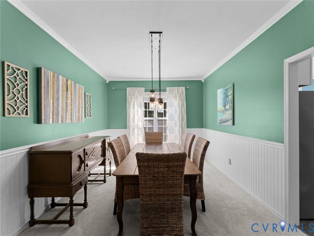 Dining space featuring wainscoting, crown molding, and a multi-bulb linear pendant light fixture