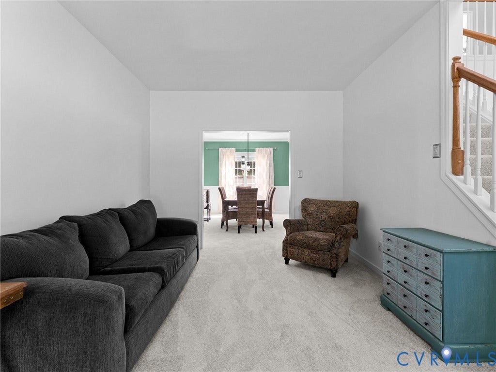 Carpeted living space with a staircase featuring wood handrails and white balusters