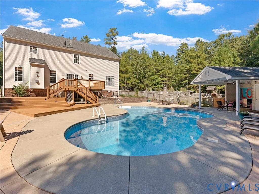 Siding exterior with multiple windows, multi-level wood deck, freeform swimming pool, and a poolside structure with a covered patio