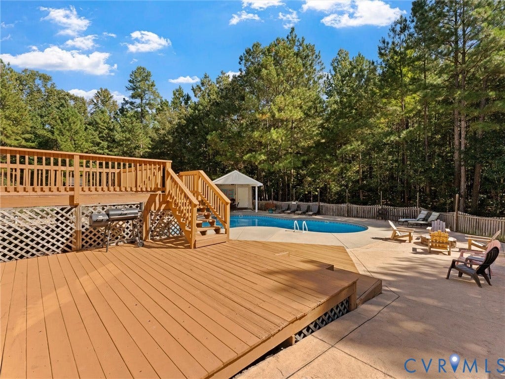 Expansive multi-level wood deck, lattice skirting, and a concrete patio surrounding a built-in swimming pool