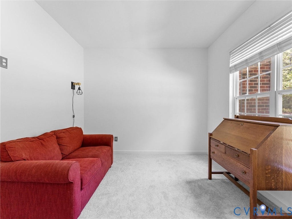 Wall-mounted light fixture, window with blinds, and light-colored carpeting