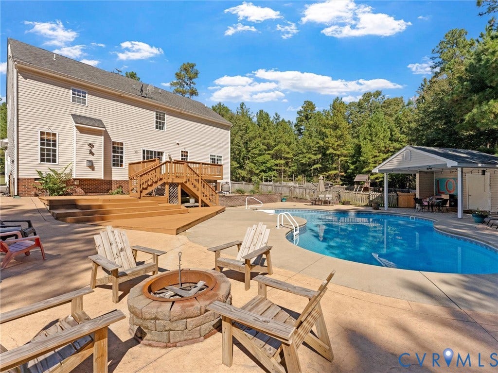 Outdoor living space featuring a swimming pool, wood deck, and fire pit