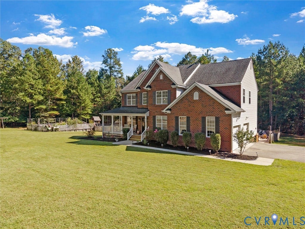 Brick and siding exterior with a covered porch, two-car garage, and established landscaping