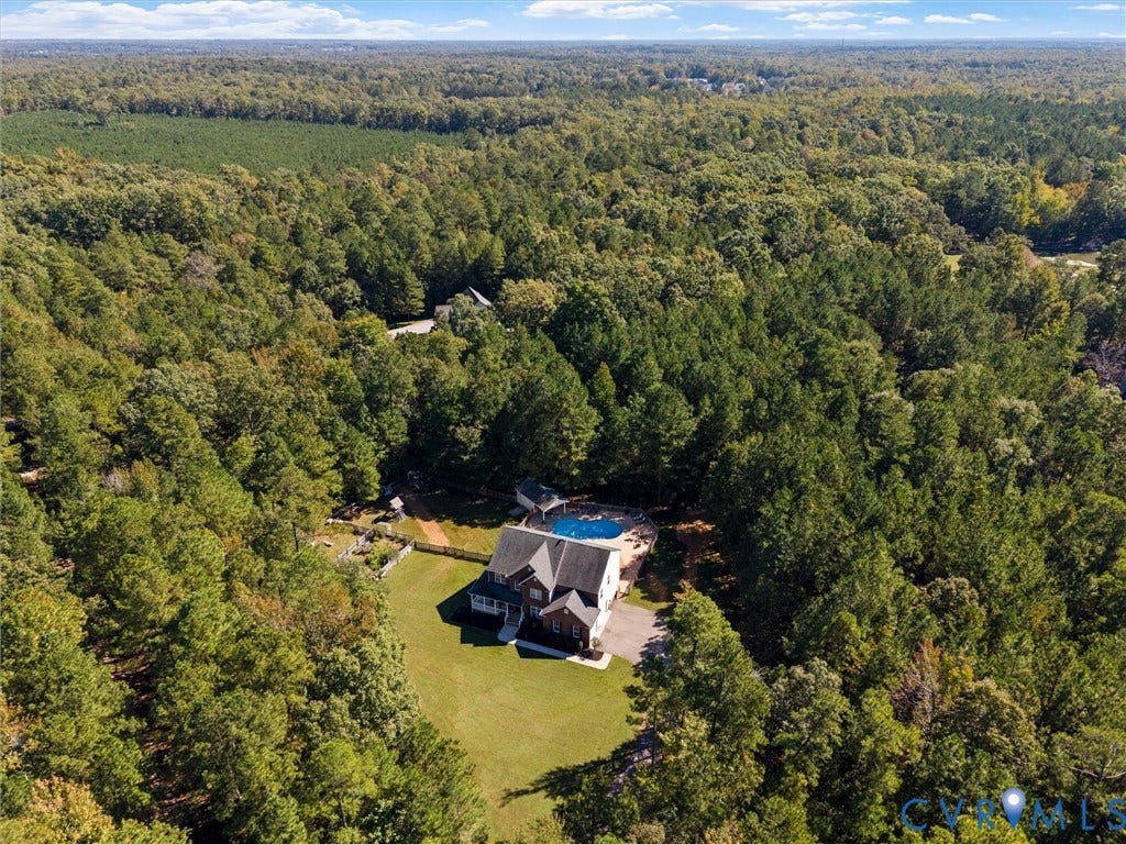 Expansive wooded grounds featuring a residential structure, a swimming pool, and a manicured lawn area